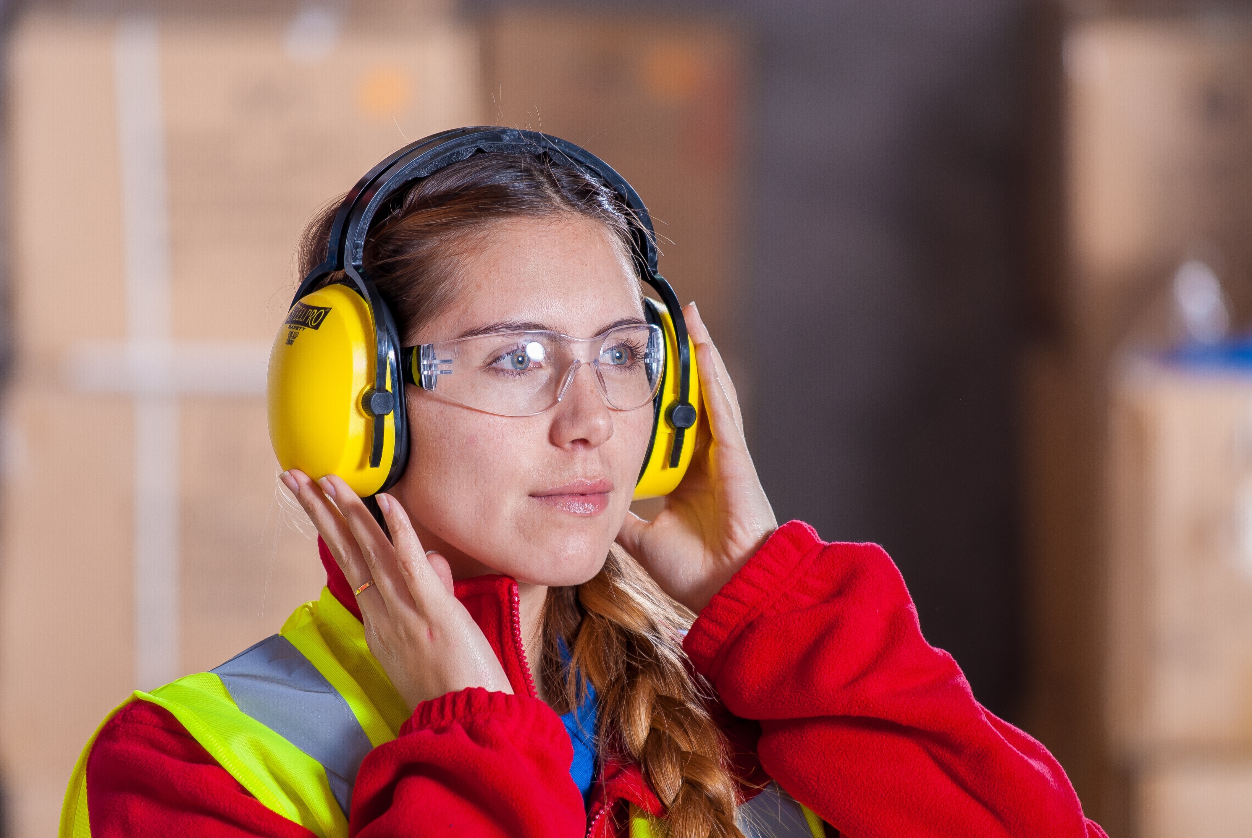 Worker wearing hearing protection, eye protection, and high visibility vest